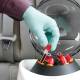 Globe Scientific GCC-P Portable Clinical Centrifuge - A Gloved hand placing a Test Tube with red liquid into the right side of a centrifuge inside a car Close-up View (Test tubes are sold separately)