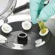 Globe Scientific GCC-P Portable Clinical Centrifuge - A Gloved Hand placing a Test Tube with yellow liquid into a Centrifuge Close-up View (Test tubes are sold separately)